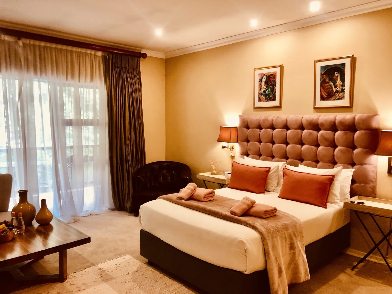 The Peach Suite — a made bed, soft linen, and balcony light